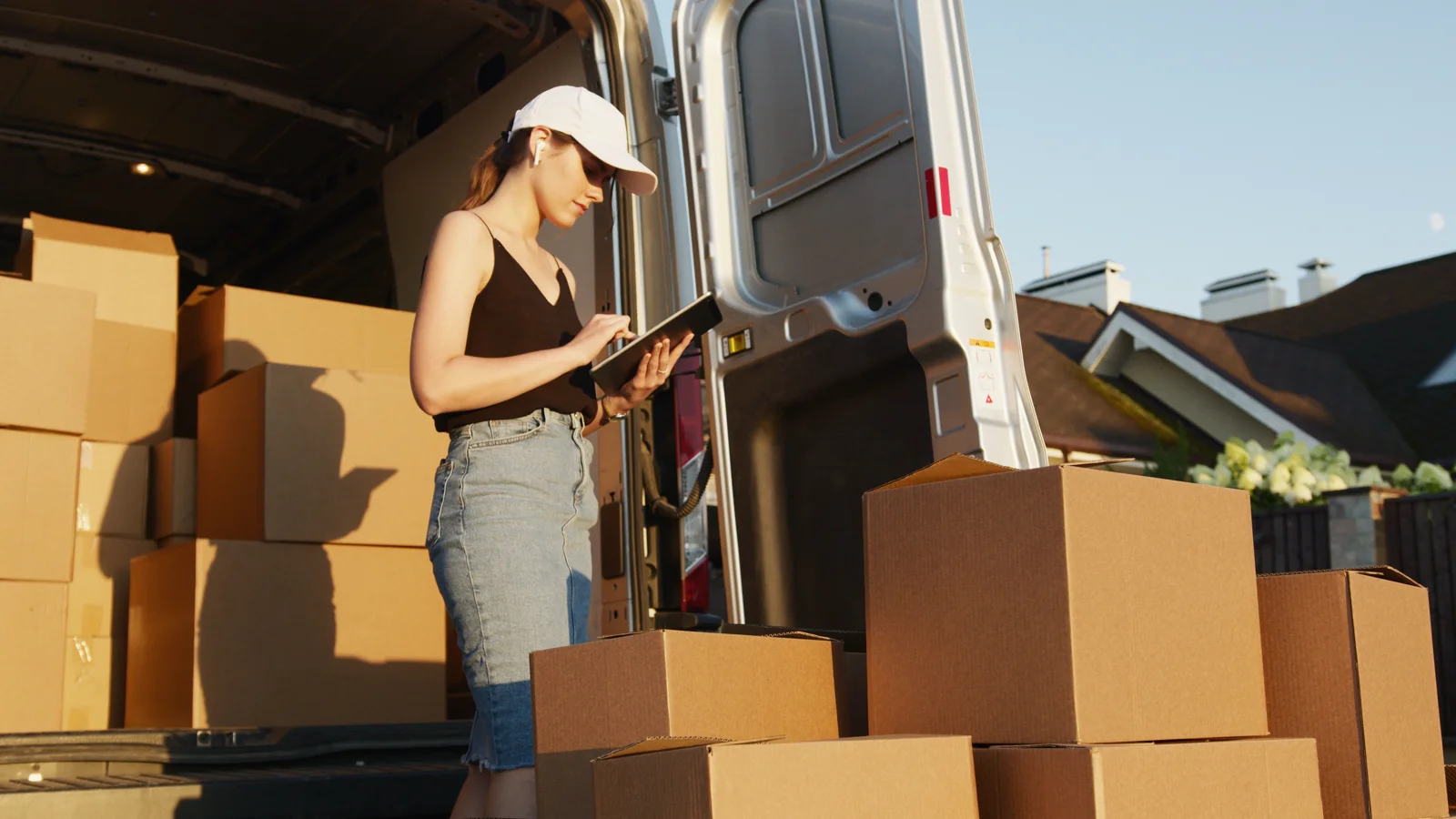 A delivery worker reviewing shipment details beside a loaded van