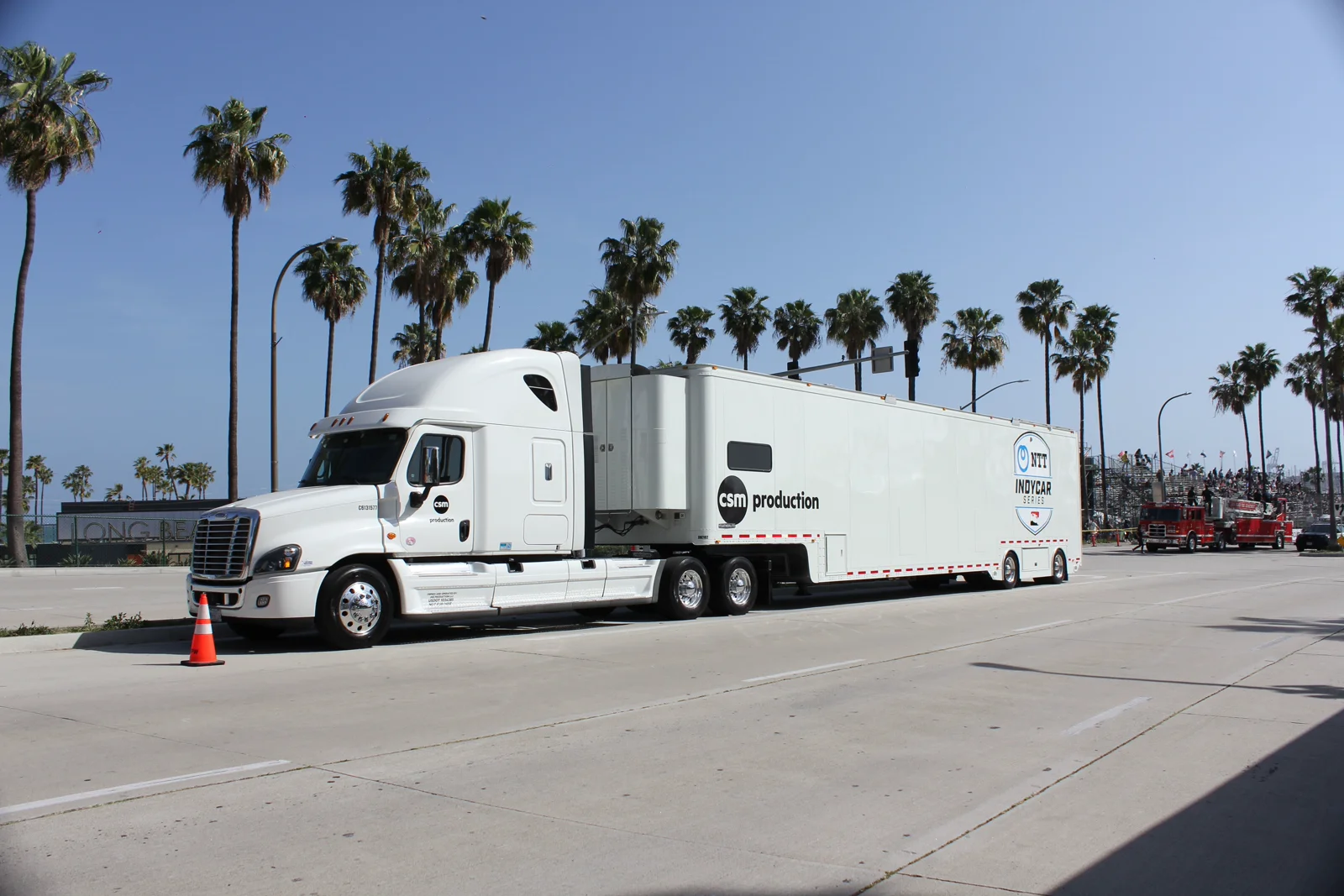 A tractor trailer parked beside palm trees in Long Beach